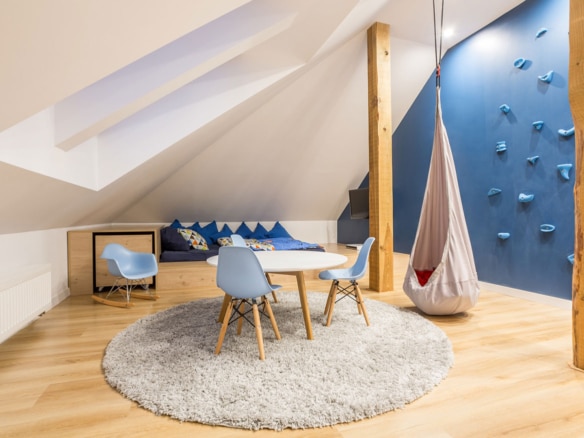 Modern attic playroom with blue accents, a climbing wall, and cozy seating.